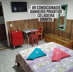 弗洛里亚诺波利斯Pousada Quintal Verde Floripa的一间卧室配有一张床、一张桌子和一台电视。