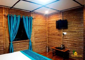 达纳尔蒂Bamboo Junction Resort - Kanatal, Valley & Mountain View的一间卧室配有一张带蓝色窗帘的床和一扇窗户