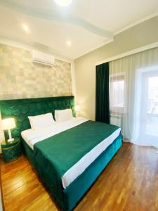 库塔伊西Hotel Orange Kutaisi的一间卧室,卧室内设有一张绿色大床