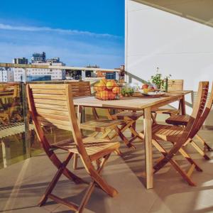 坎佩略Apartement Verano El Campello - 2 Bedrooms - Piscina - Garaje的阳台上的木桌和椅子