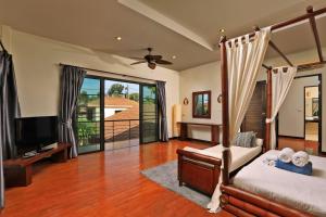 拉威海滩热带景观沙利卡别墅的一间卧室配有一张床、一台电视和一个阳台