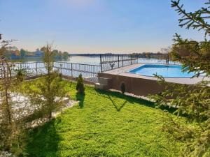 TîncăbeştiSnagov Lakeview Residences的游泳池在水体旁边的院子