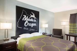 尤金Gateway Inn & Suites Eugene-Springfield的酒店客房的墙上设有一张带标志的床