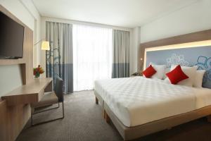 马六甲Noble Resort Hotel Melaka的酒店客房设有一张大床和一张书桌。