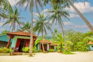 富国吉吉椰子海滩度假村的海滩上一排种有棕榈树的简易别墅