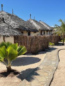 MambruiMambrui Golden Beach Bar and Cottages的草屋顶和棕榈树的建筑