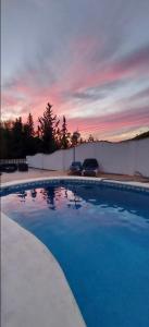 贝纳马奥马Casa Benamahoma的蓝色的游泳池,背景是日落