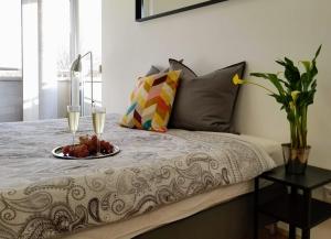 布达佩斯New Pest Apartman的一张带一盘水果和两杯葡萄酒的床