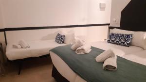 塞维利亚Hostal Hom Museo的客房内的两张床和毛巾