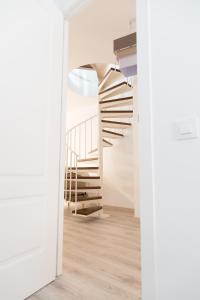 菲格拉斯Spiral Stairs Duplex的白色客房的螺旋楼梯,铺有木地板