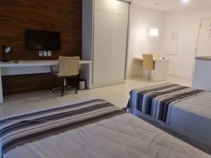 巴西利亚Flat Particular - SHN - Vista Livre Esplanada的酒店客房设有两张床、一张桌子和一台电视。