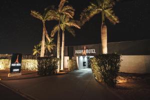 MatãoParis Motel的一座棕榈树建筑,一个标牌读取付费酒店