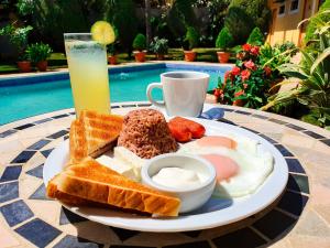 马那瓜Hotel Los Pinos的桌上的一盘早餐食品和饮料