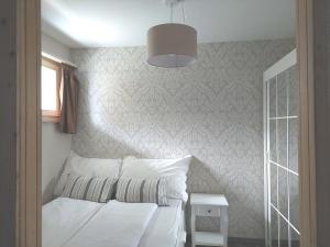 莱克斯LAAX Central Holiday Apartment with Pool & Sauna的一间卧室配有一张带白色床单和一盏灯的床。