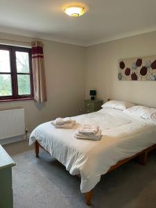 卡姆尔福德Rose Cottage的一间卧室配有一张大床和毛巾