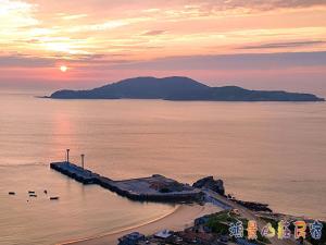 Juguang鴻景山莊民宿 b&B的海滩上的日落,在水中放鸭子