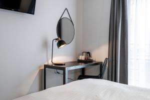 布鲁塞尔贝弗利山酒店的一间卧室配有一张带镜子的桌子和一张床