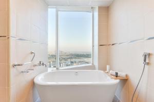 迪拜Nassima Tower Hotel Apartments的带窗户的浴室内的白色浴缸