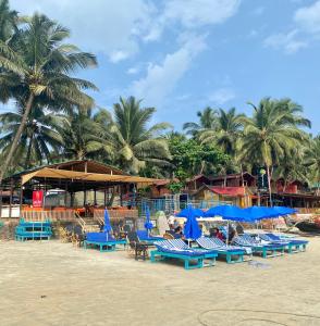 帕罗林Chill Out Jasmine Restaurant Bar Rooms的海滩上一群蓝色沙滩椅和遮阳伞