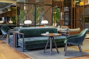 米兰米兰美利亚酒店的大堂设有绿色的沙发、椅子和桌子