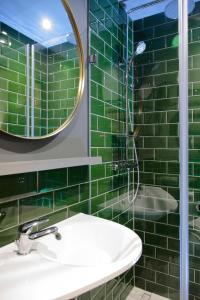 布达佩斯Leo Boutique Rooms - Adults Only的绿色瓷砖浴室设有水槽和镜子
