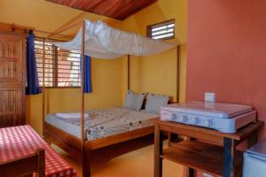 阿姆巴托洛阿卡Colibri Lodge的一间卧室配有一张带天蓬和桌子的床