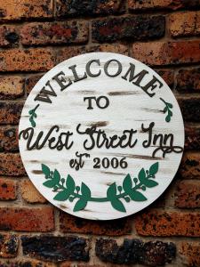 埃尔默洛West Street Inn - Ermelo的砖墙上的标志,上面写着欢迎来西街旅馆