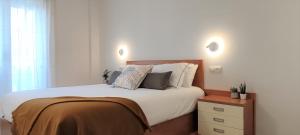 奥洛特Apartament Natura amb Calma的卧室配有一张带白色床单和枕头的大床。