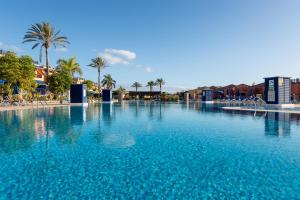 圣巴托洛梅Sunset House in Meloneras by Ten properties的一座拥有蓝色海水和棕榈树的大型游泳池