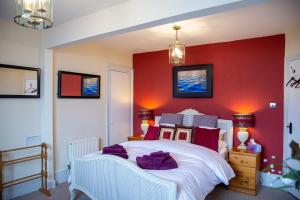 海斯廷斯Seagulls Nest Beachfront Apartment With 3 Bedrooms的卧室配有白色的床铺和红色的墙壁