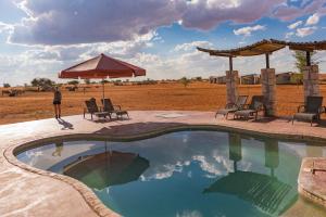 马林塔尔Kalahari Anib Camping2Go的一个带椅子和遮阳伞的游泳池