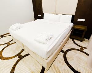 阿拉木图East Palace Hotel的一张带白色床单和毛巾的床