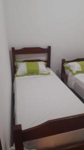 马拉戈日Condominio Oliveira的一间卧室配有两张带白色和绿色枕头的床