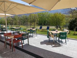 蒙特卡罗索Hotel Bellinzona Sud Swiss Quality的一组桌椅和遮阳伞