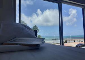 萨尔瓦多Puleiro Hostel的床上的书籍,享有海滩美景