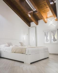 米兰Residenze Niguarda的一间白色卧室,卧室内配有一张床铺,房间拥有木制天花板