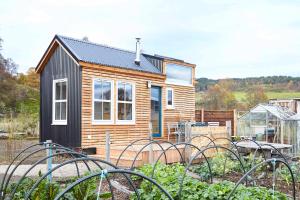 巴拉特Unique tiny house with wood fired roll top bath in heart of the Cairngorms的一座小木房子,前面设有一个花园