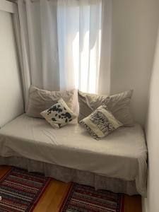 瓜鲁柳斯Quartos Vila Augusta/Guarulhos的一张带枕头的床和一个窗户