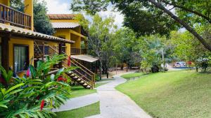 马塔迪圣若昂Loft Reserva Sapiranga Praia do Forte Vila Hen 102的一条走道,旁边是一座黄色的房子,有院子