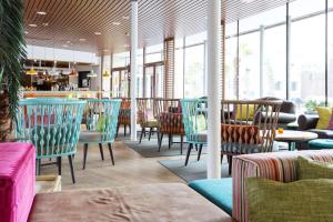 腓特烈港瑞夫斯堪迪克酒店的餐厅设有多彩的桌椅和窗户。