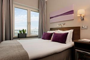 哥德堡斯堪第25号酒店的一间卧室配有一张带紫色枕头的床和窗户。