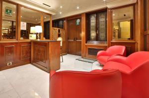 热那亚摩登威尔第贝斯特韦斯特酒店的一间设有红色椅子和书桌的等候室
