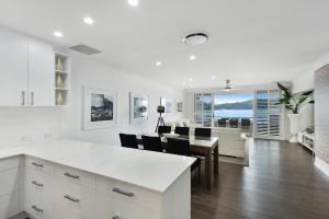 汉密尔顿岛Frangipani Beachfront Lodge 202 on Hamilton Island by HamoRent的厨房以及带桌椅的起居室。