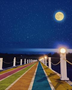 美娜多NDC Resort & Spa的夜间与天空中的月亮一起走的木板路