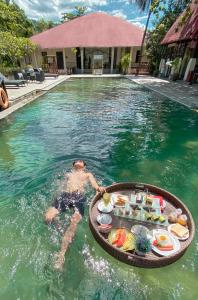 美娜多NDC Resort & Spa的游泳池里的人,带一盘食物