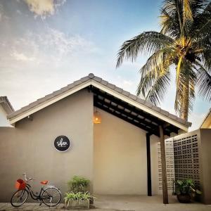 恰洛克拉姆Silan Residence, Koh Phangan - An authentic village experience的停在棕榈树建筑外的自行车