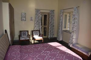 比卡内尔Roda House - a boutique homestay in Bikaner的一间卧室配有一张紫色的床和两把椅子