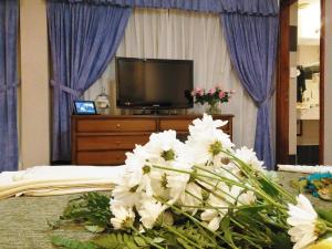 布宜诺斯艾利斯Hotel Irun的一间卧室配有电视,床上有白色的鲜花