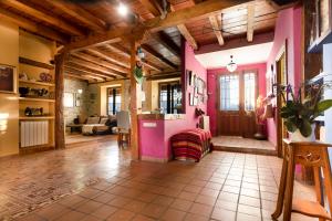 La ParrillaCasa Rural La Moderna的客厅拥有粉红色的墙壁和木制天花板。