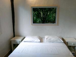 朱奎Pousada Baobá的卧室配有一张带两张桌子的床,墙上挂着一张照片
